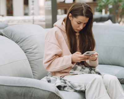 Zieke vrouw zit met een smartphone in haar hand op een bank